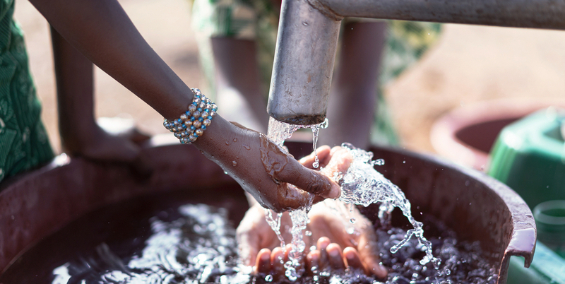 Mani che raccolgono acqua potabile da una fontana, simbolo di accesso all’acqua sicura grazie a soluzioni sostenibili come Warka Water.