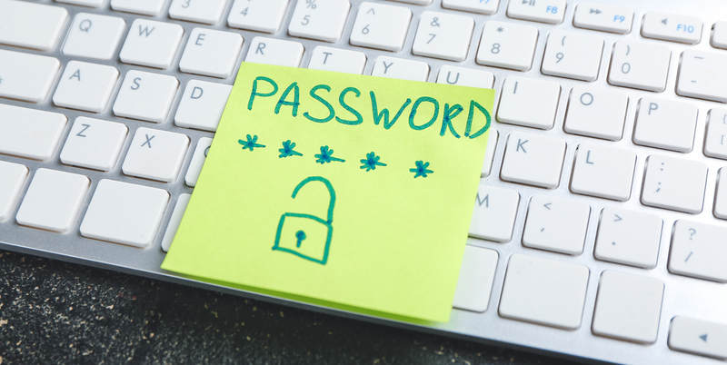 Post-it con la scritta "PASSWORD" e un lucchetto disegnato, appoggiato su una tastiera di computer, simbolo delle cattive abitudini nella gestione delle credenziali di accesso.